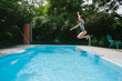 © Maria Manco/Stocksy - Girl jumps into backyard pool