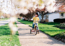 Boy Rides Tricycle Down Sidewalk