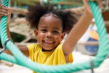 Portrait Of Smiling Girl Climbing Rope Net At Outdoor Playground