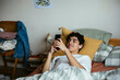 © BONNINSTUDIO/Stocksy - Teen boy using phone in bed