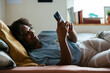 © BONNINSTUDIO/Stocksy - Teen girl using phone in bed