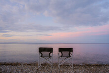 Two Chairs On The Background Of Seaside In Sunset 