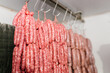 © Ezequiel Giménez/Stocksy - Row of fresh sausages hanging on hooks in store