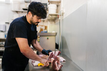 Man Cutting Fresh Meat In Kitchen