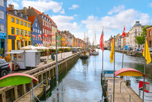 Colorful Buildings With Apartments, And Shops Alongside Outdoor Sidewalk Cafes And Docked Sailboats At The 17th Century Nyhavn Canal, A Major Tourist Destination In The City Of Copenhagen, Denmark.