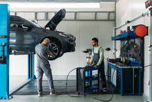 Two Mechanics Repairing Car In Garage 
