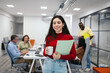 © Pedro Merino/Stocksy - Portrait of a smiling young woman in a modern office