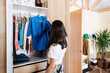 © Malquerida Studio/Stocksy - Woman selecting clothes from the closet