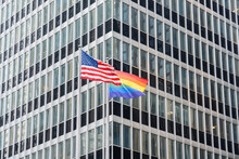 American And LGBT Rainbow Flags Holding On The Street.