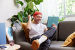 © ALTO IMAGES/Stocksy - Happy man chatting online while resting on couch
