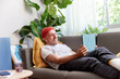© ALTO IMAGES/Stocksy - Casual man resting with tablet on couch