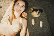 Woman Laying Near The Dog With Sunglasses On The Beach