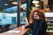 © Daniel Gonzalez/Stocksy - Cheerful black woman talking on smartphone in cafe