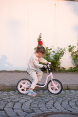 Wall Mural - A little girl in a pink suit rides a pink runner in the rays of the sunset.