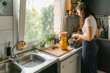 © Léa Jones/Stocksy - young woman preparing tea in kitchen