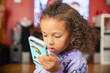 © Anya Brewley Schultheiss/Stocksy - Preschool child with curly hair using an electronic phone