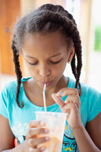 Pretty Child Drinking An Icy Drink From A Straw While Outside