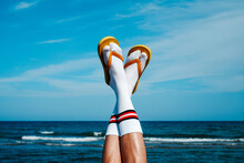 upside-down wearing socks and flip-flops on the beach