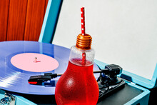Red Drink In A Lightbulb-shaped Glass On A Turntable