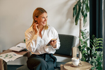 Wall Mural - Woman entrepreneur is using phone in coworking during working day. Distance work concept