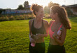 © Guille Faingold/Stocksy - Happy sportswomen with bottles during evening workout