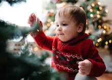 Happy Baby Decorates A Christmas Tree With String Lights