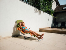 Woman Sunbaths On A Deckchair