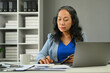 © Prathankarnpap - Successful middle age businesswoman using laptop working with statistics documents at modern office.