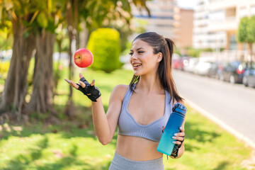 Wall Mural - Young pretty sport woman at outdoors with an apple and with a bottle of water