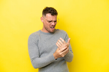 Wall Mural - Young caucasian handsome man isolated on yellow background suffering from pain in hands