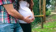© David Pereiras - Unrecognizable latin female pregnant and her partner holding belly on nature