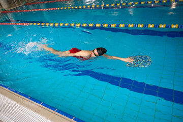 Young sportswoman practicing freestyle stroke in pool