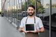 © LIGHTFIELD STUDIOS - smiling barista in apron holding digital tablet with blank screen while standing on urban street