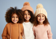 Three Little Girls Wearing Comfy Warm Clothes And Wool Hats In Pastel Colors, Posing And Smiling. Fall Winter Fashion For Kids. Generative AI