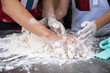 © Surachetsh - Two skilled Asian men showcase their expertise as they deftly work together, their four hands skillfully kneading and threshing flour on aluminum plate, in preparation for crafting fresh