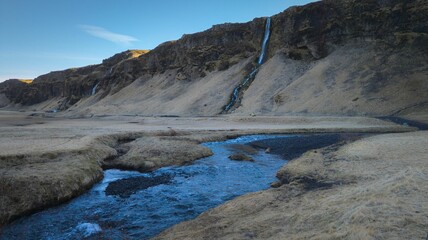 Sticker - Stunning landscape of a majestic waterfall surrounded by an expanse of dry, golden grass