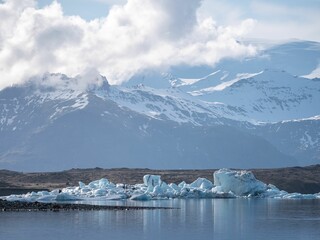 Sticker - Picturesque landscape of an iceberg in the water with a backdrop of snow-covered mountains