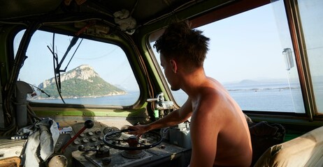 Sticker - Caucasian man with no shirt while casually driving in a boat in Sardinia, Italy