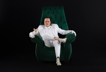 Wall Mural - rich man in a white suit sits in a chair, black studio background