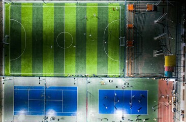 Wall Mural - Aerial shot of a well-lit soccer field with players in the stadium at night