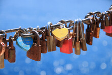Close Up Of Old Rusty Love Locks On Chain Against Background Of Blue Sea On Sunny Day. Close Up Of Old Rusty Love Locks On Chain Against Background Of Blue Sea On Sunny Day. Trip For Valentines Day 