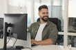 © New Africa - Happy man working on laptop in open plan office