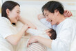 © taka - ベッドで赤ちゃんと添い寝する夫婦