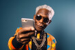 © Mihai Zaharia - Amusing image of a senior African American man dressed in trendy streetwear, striking a cool pose while taking a selfie with a smartphone. Generative AI