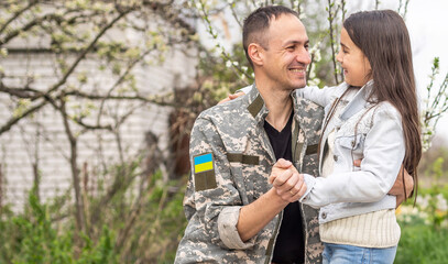 Wall Mural - Soldier in Ukrainian military uniform hugging his daughter. Family reunion