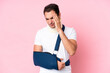© luismolinero - Young caucasian man with broken arm and wearing a sling isolated on pink background with headache
