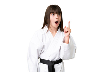 Wall Mural - Little Caucasian girl doing karate over isolated background thinking an idea pointing the finger up