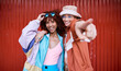 © Wesley/peopleimages.com - Fashion, gen z or portrait of friends in city on red background in streetwear with fashion or style together. Urban, women or excited people hug with happiness, smile or freedom on holiday vacation