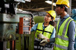 © offsuperphoto - worker or engineer training and teaching how to use machine control with coworker in factory