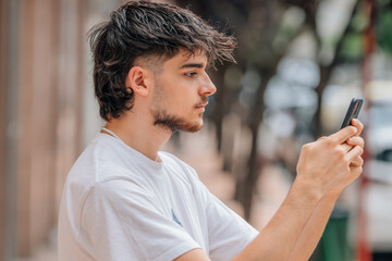 Sticker - portrait of young man in the street looking at the mobile phone